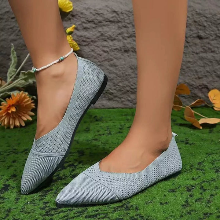 Sage pointed toe knit flats worn on grass, side view with an anklet