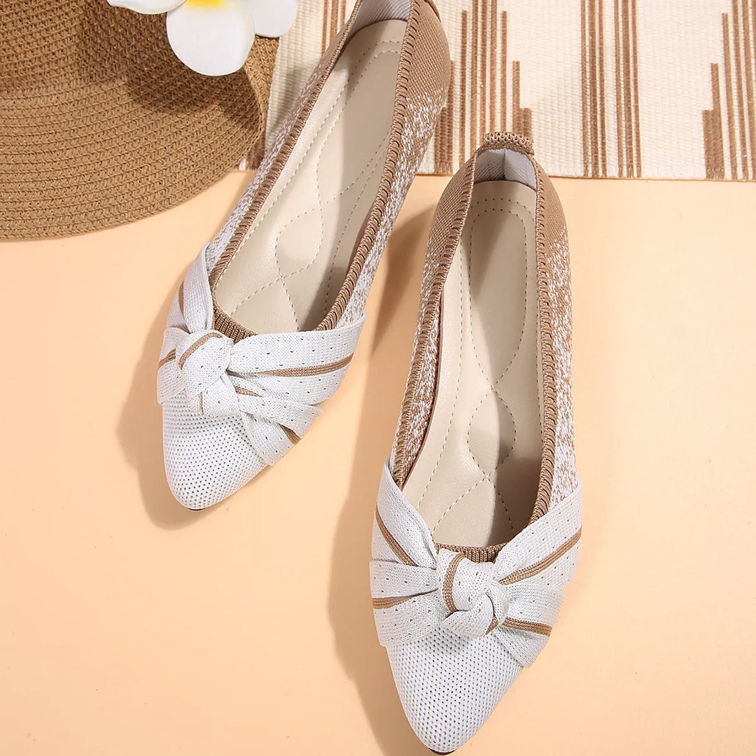 White pointed toe flats with a knotted bow, top view of the pair