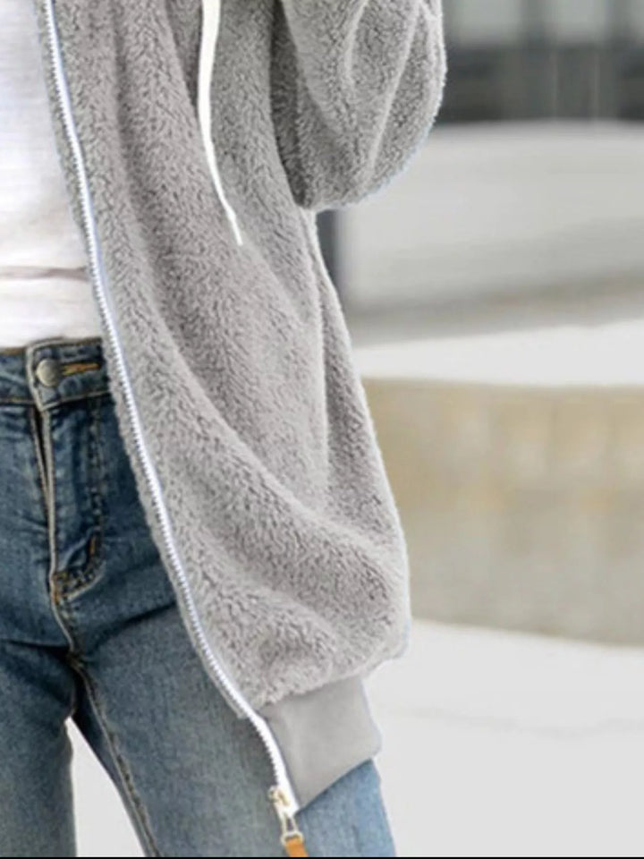 Light gray fleece jacket sleeve and zipper detail with jeans