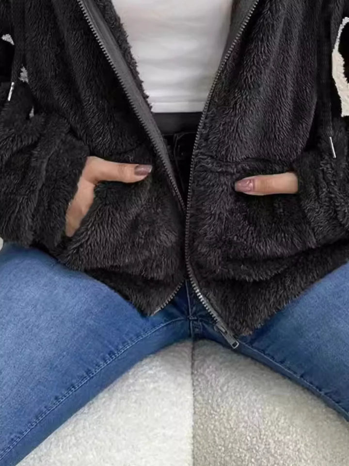 Detail of black fleece jacket with hand in the front pocket and fuzzy texture