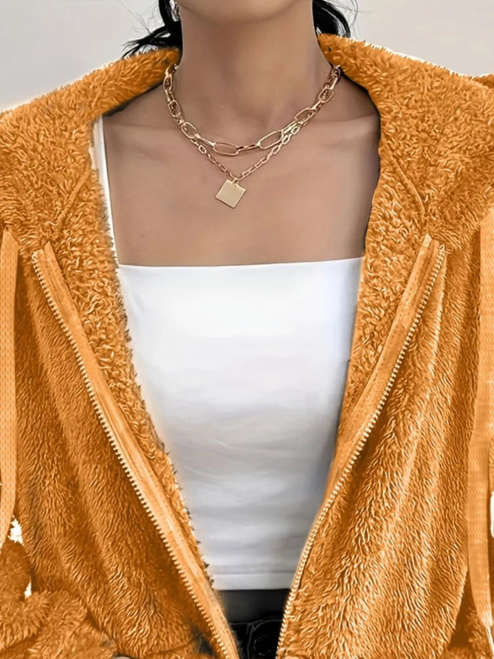 Detail of orange fleece jacket with hand in the front pocket and fuzzy texture