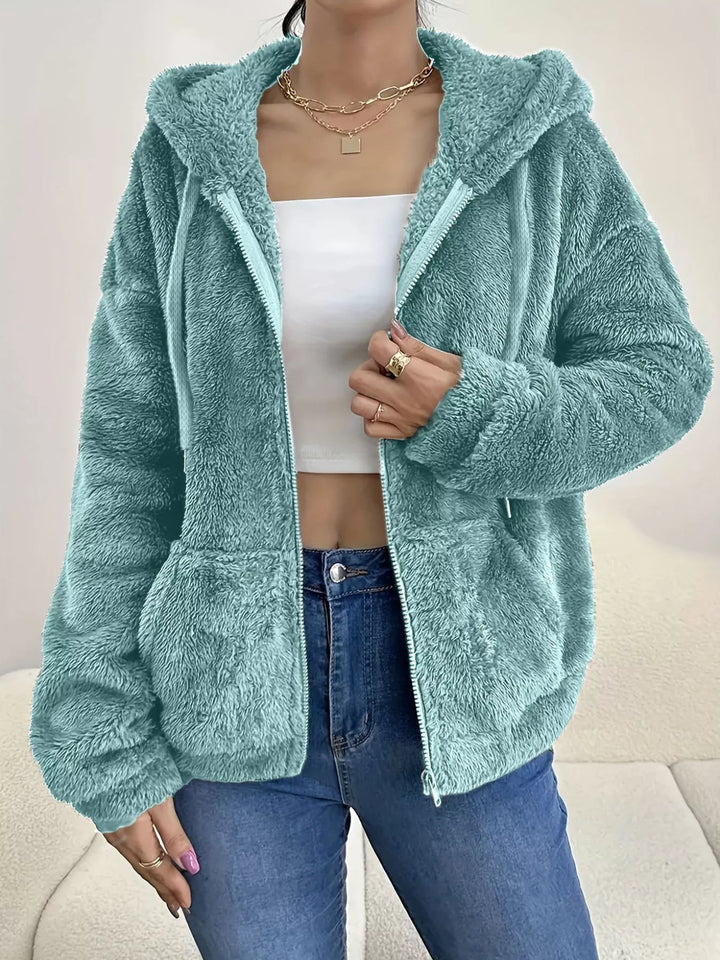 Seafoam hooded zip up fleece jacket with drawstring hood over a white top and jeans