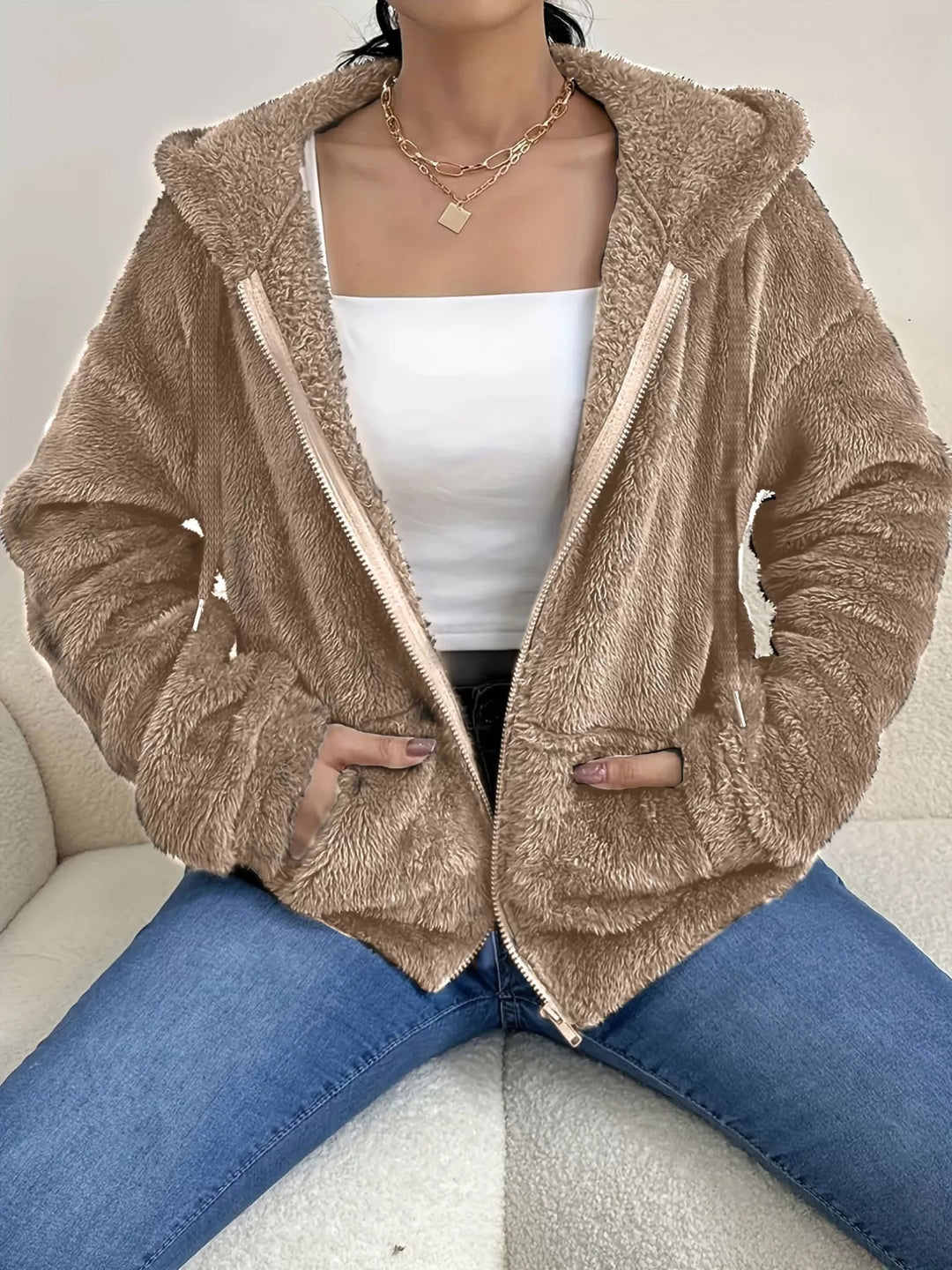 Taupe hooded zip up fleece jacket with drawstring hood over a white top and jeans