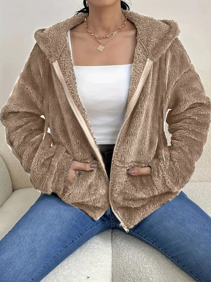 Taupe hooded zip up fleece jacket with drawstring hood over a white top and jeans