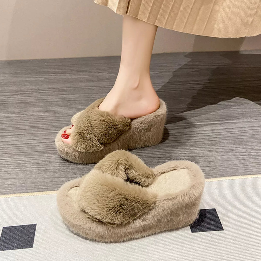 Tan fluffy platform slide on foot with a pleated skirt, resting on a rug