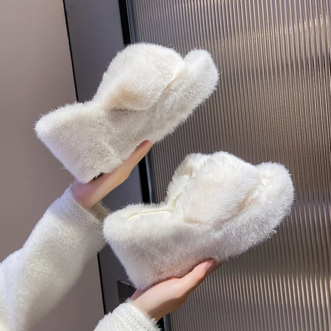 White fluffy wedge slippers held up to show the crossed straps and platform