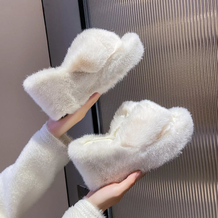White fluffy wedge slippers held up to show the crossed straps and platform