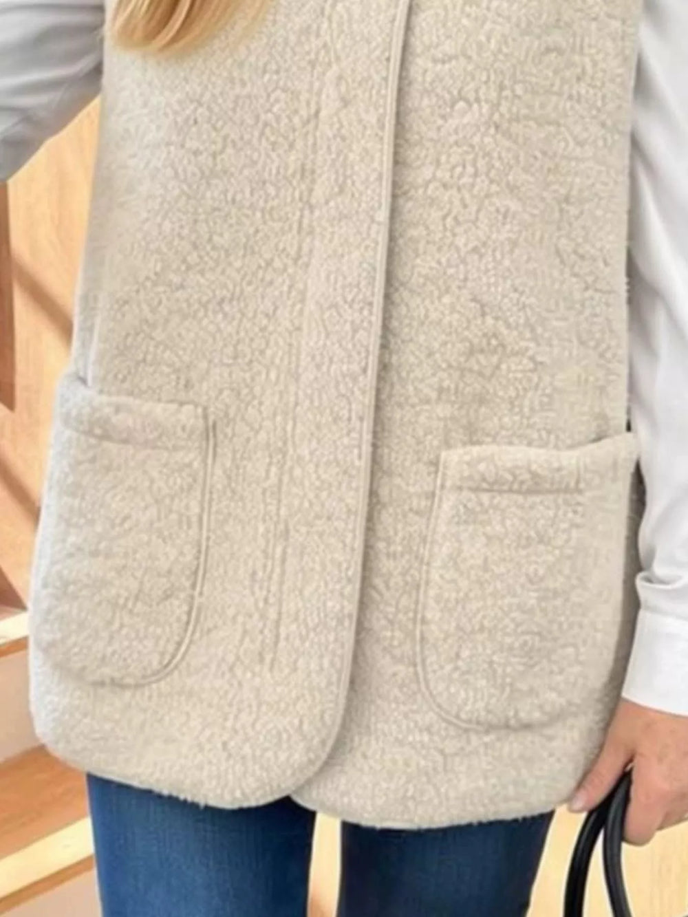 Close-up of the beige fuzzy vest patch pockets and front closure