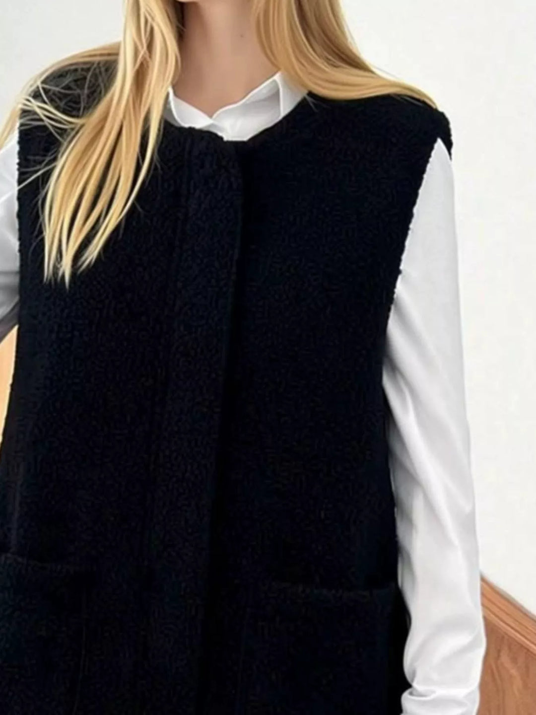 Close-up of the black fuzzy vest texture and patch pockets