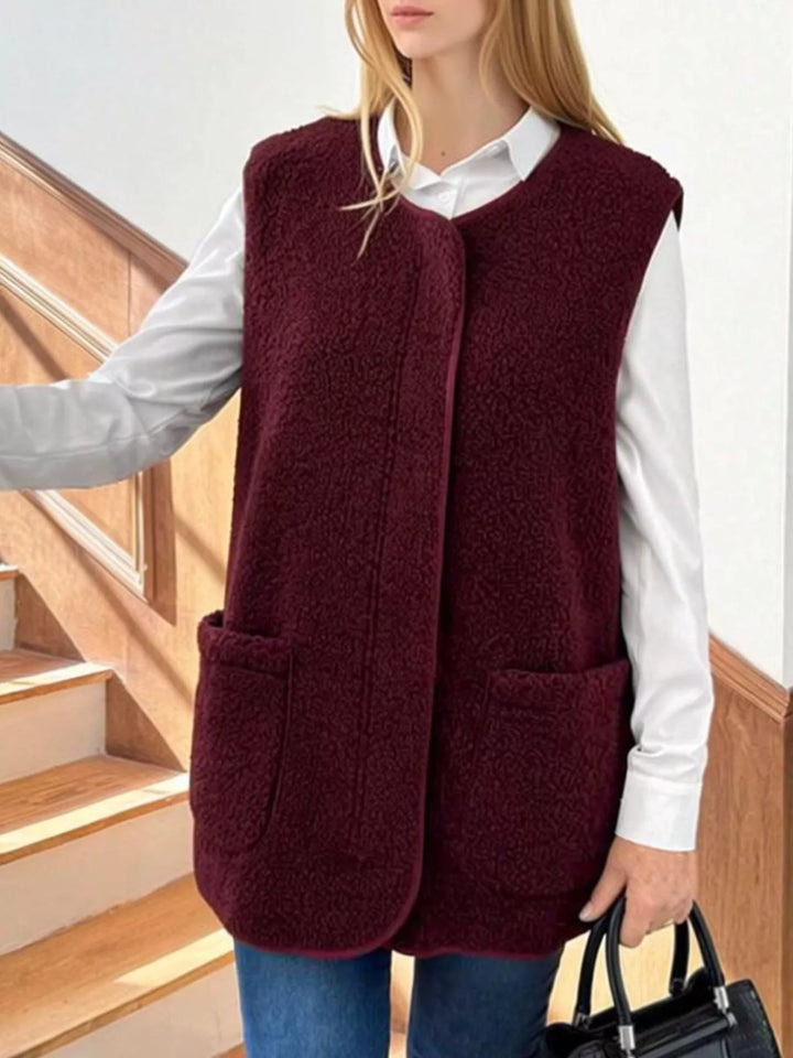 Burgundy fuzzy vest with a round neck and patch pockets, worn with jeans