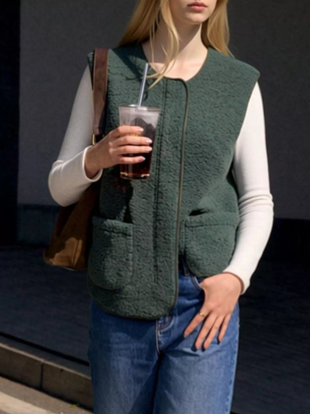 Forest green fuzzy vest styled with jeans and a tote bag, holding an iced drink