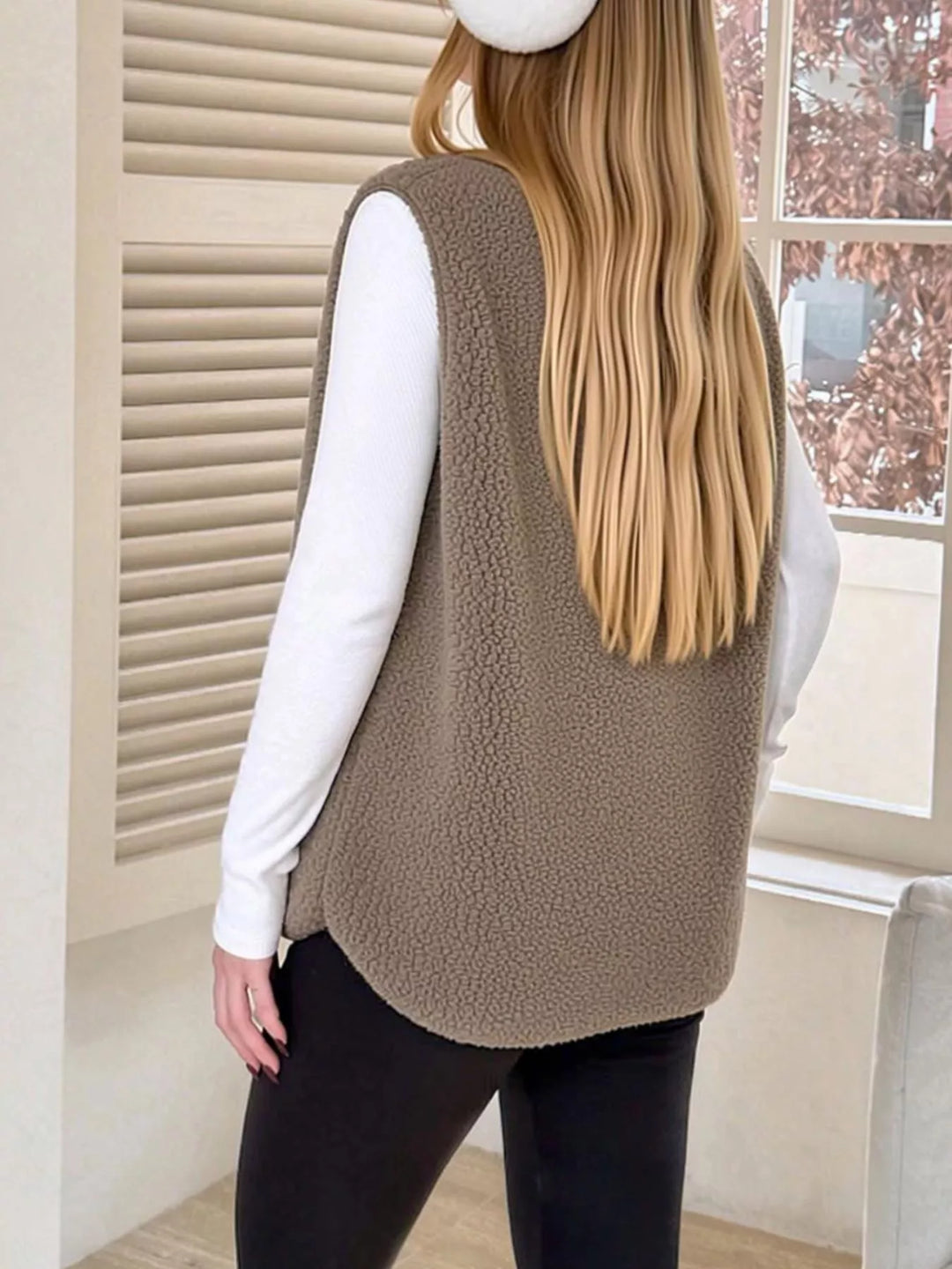 Back view of the taupe fuzzy vest with a curved hem