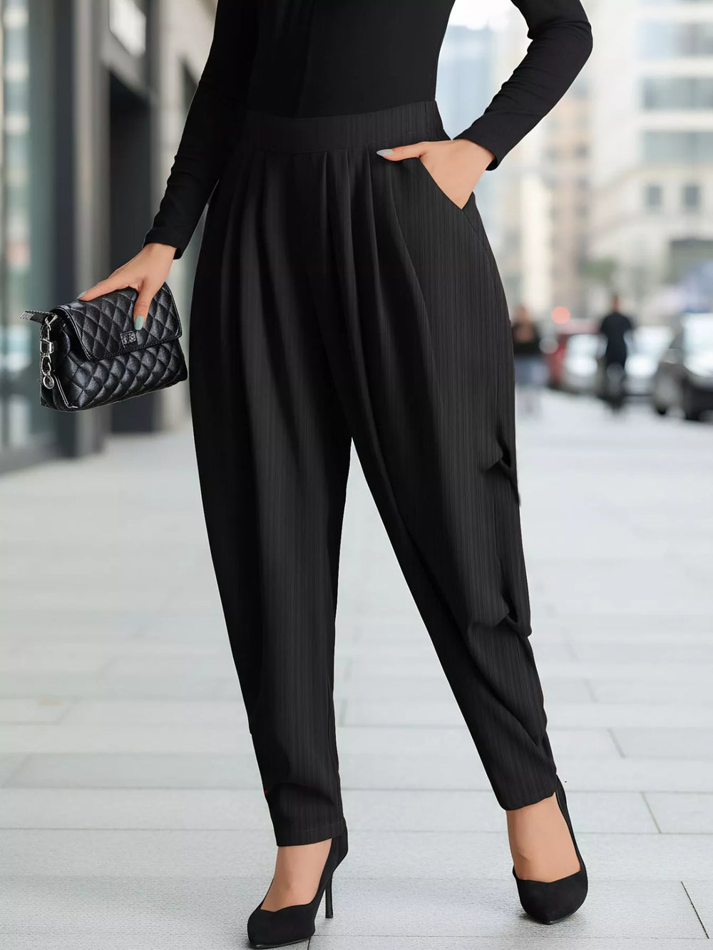 Black pleated harem pants worn with a black top, heels and a quilted clutch