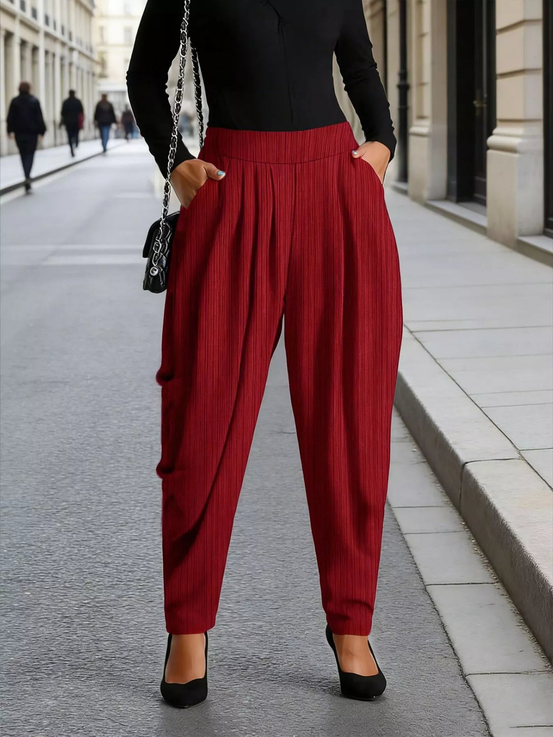 Burgundy pleated harem pants worn with a black long sleeve top and heels