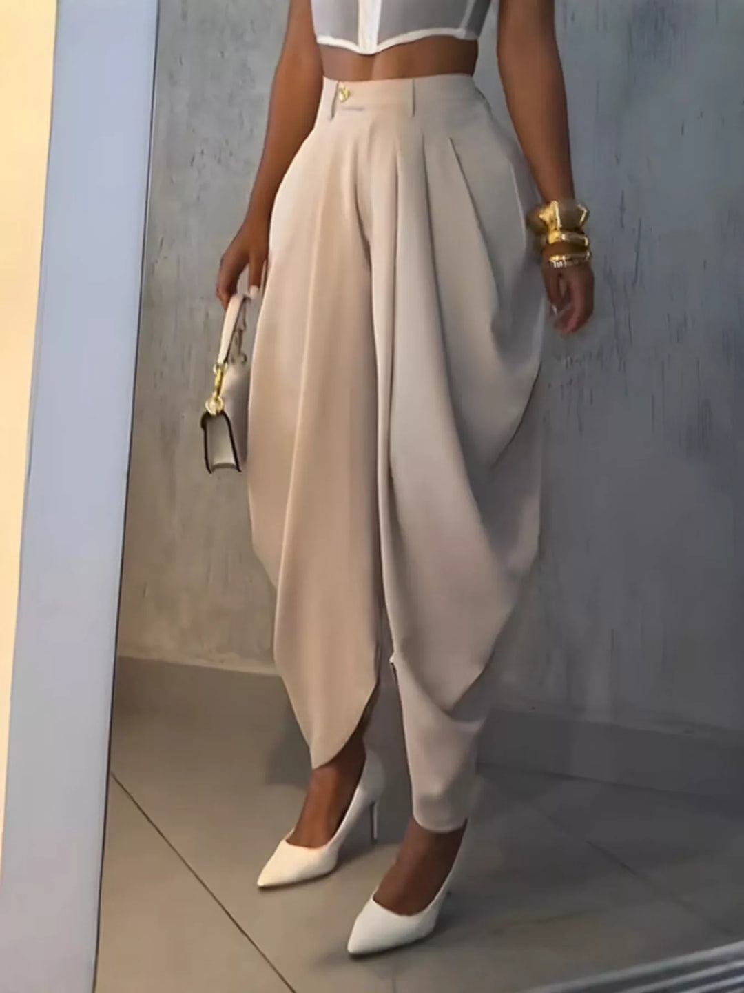 Beige high waisted harem pants with pleats, styled with a sheer corset top