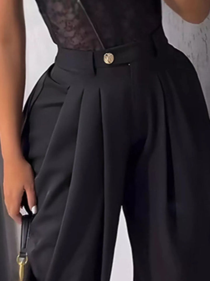 Close-up of black high waisted harem pants with gold button and deep pleats