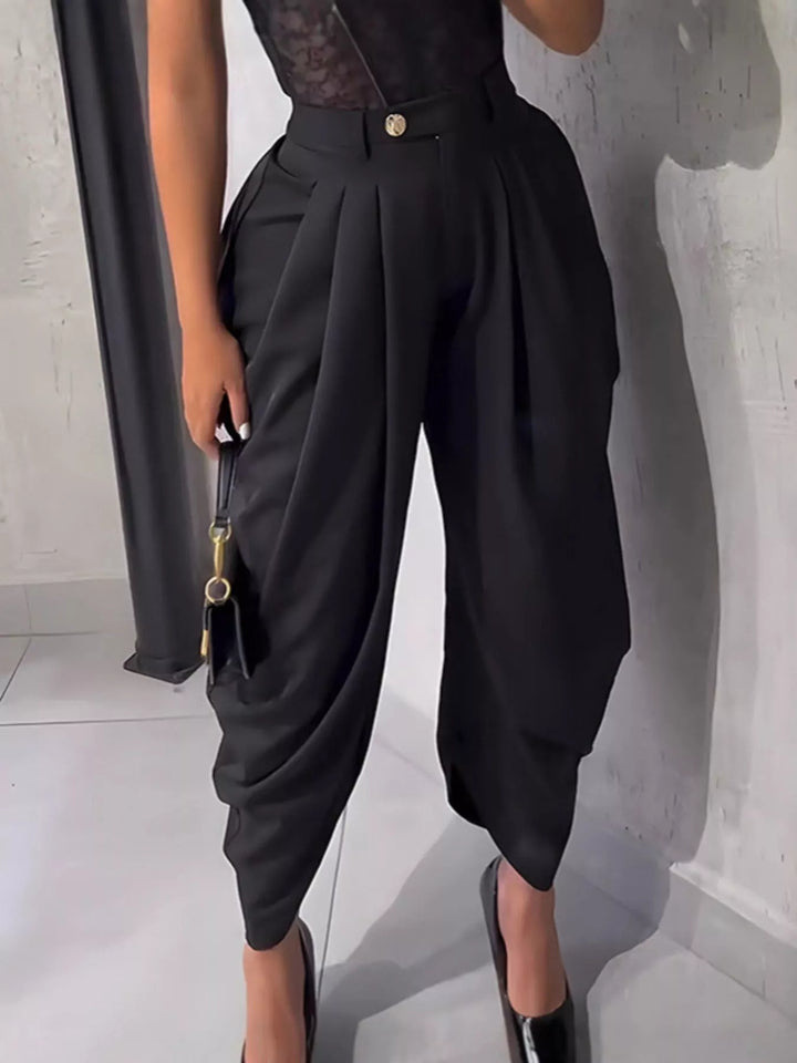 Black pleated harem pants worn with a lace bodysuit and pointed pumps