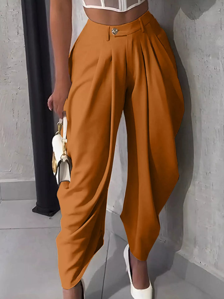 Burnt orange harem pants with a high waist and pleats, paired with white heels