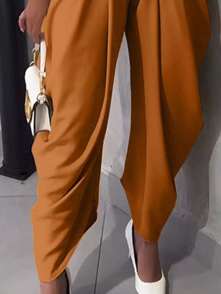 Burnt orange harem pants side view showing the draped tapered hem