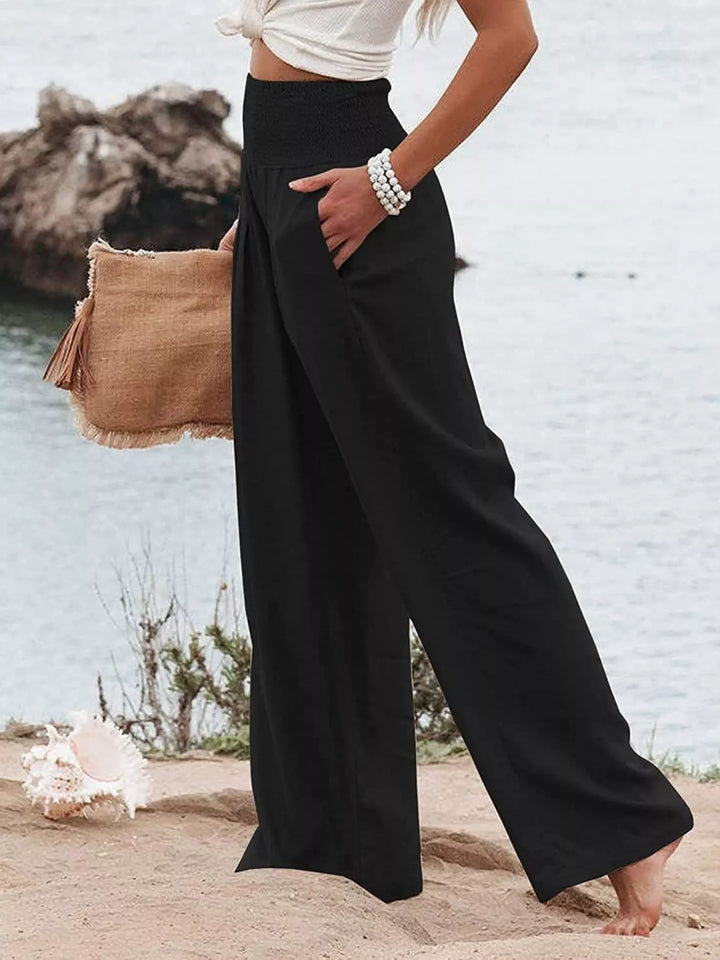 Black wide leg pants with a hand in the pocket, angled beach view