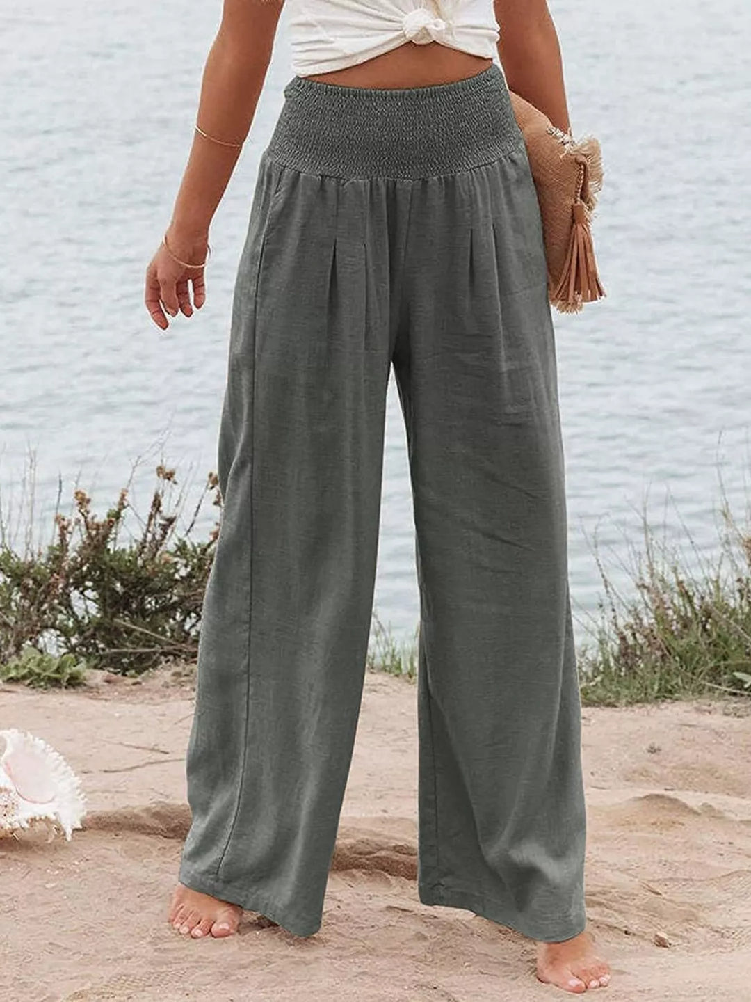 Charcoal wide leg pants with smocked waist, worn with a woven clutch