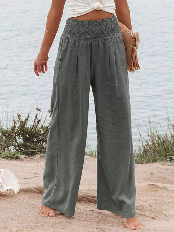 Charcoal wide leg pants with smocked waist, worn with a woven clutch