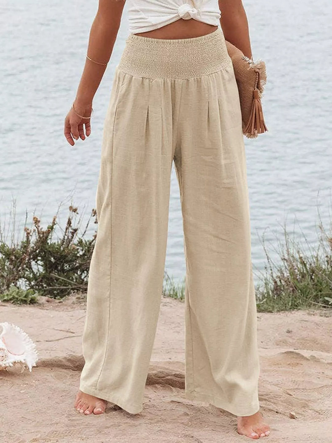 Light sand high waisted wide leg pants with smocked waist, beach front view