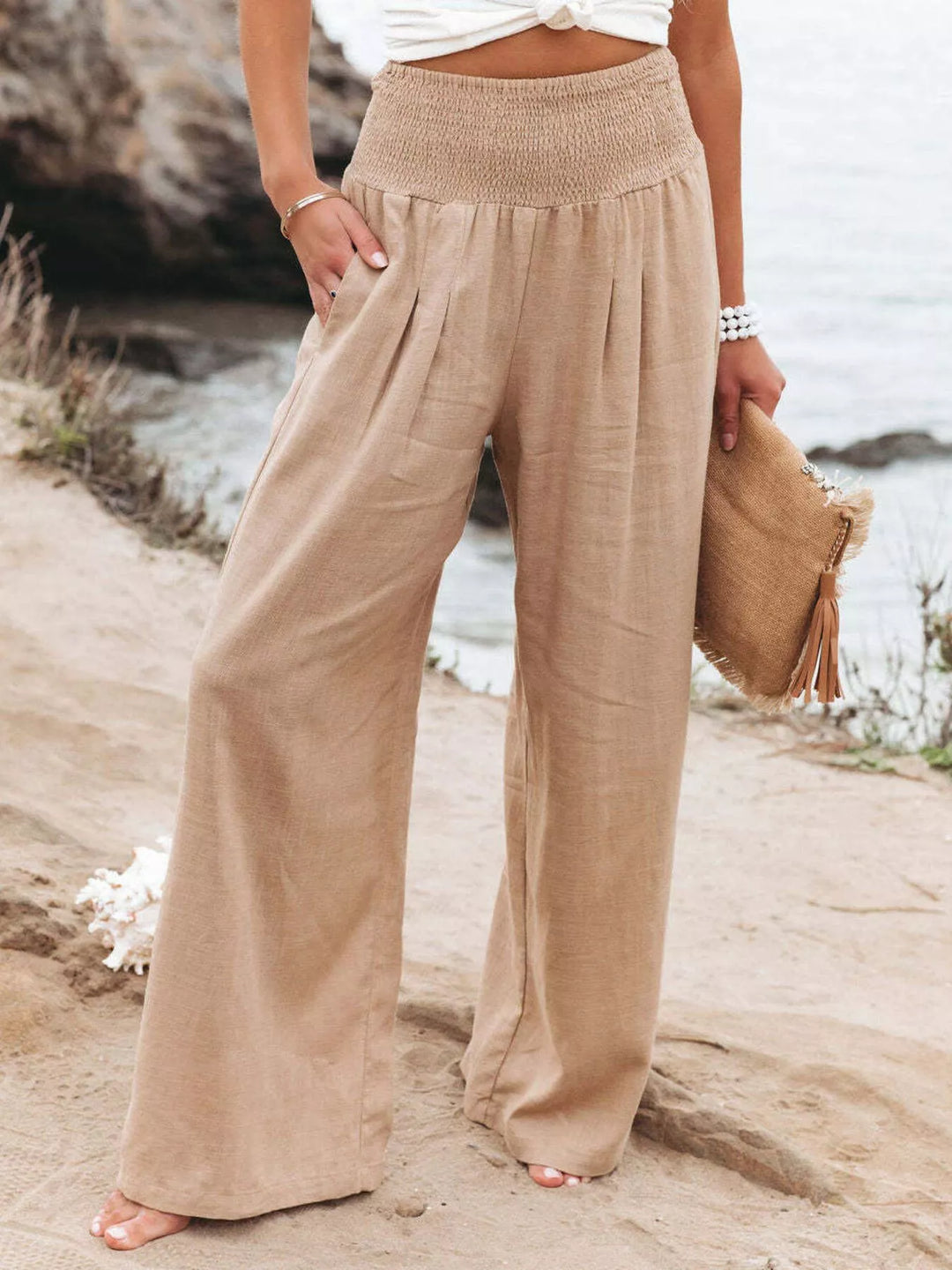 Sand toned wide leg pants with smocked waist, front view with clutch