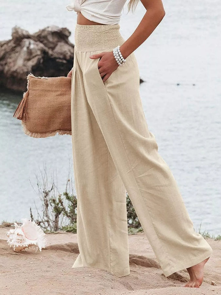 Light sand wide leg pants in a walking side pose with hand in pocket