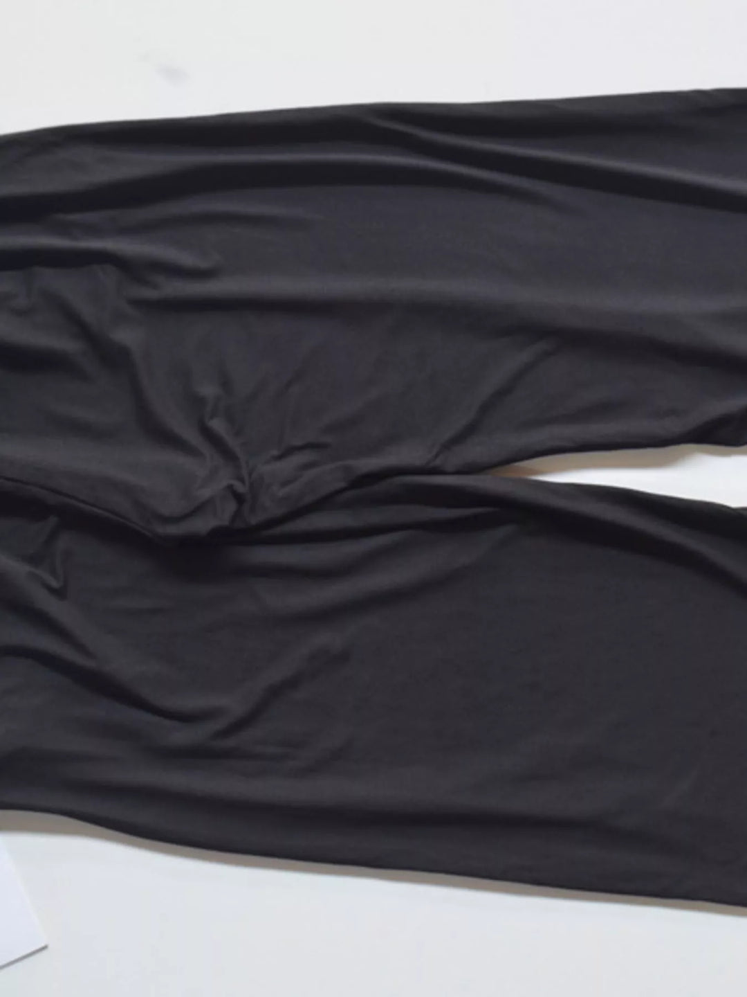 Black high waisted wide leg pants, close-up of fabric folds at the hem