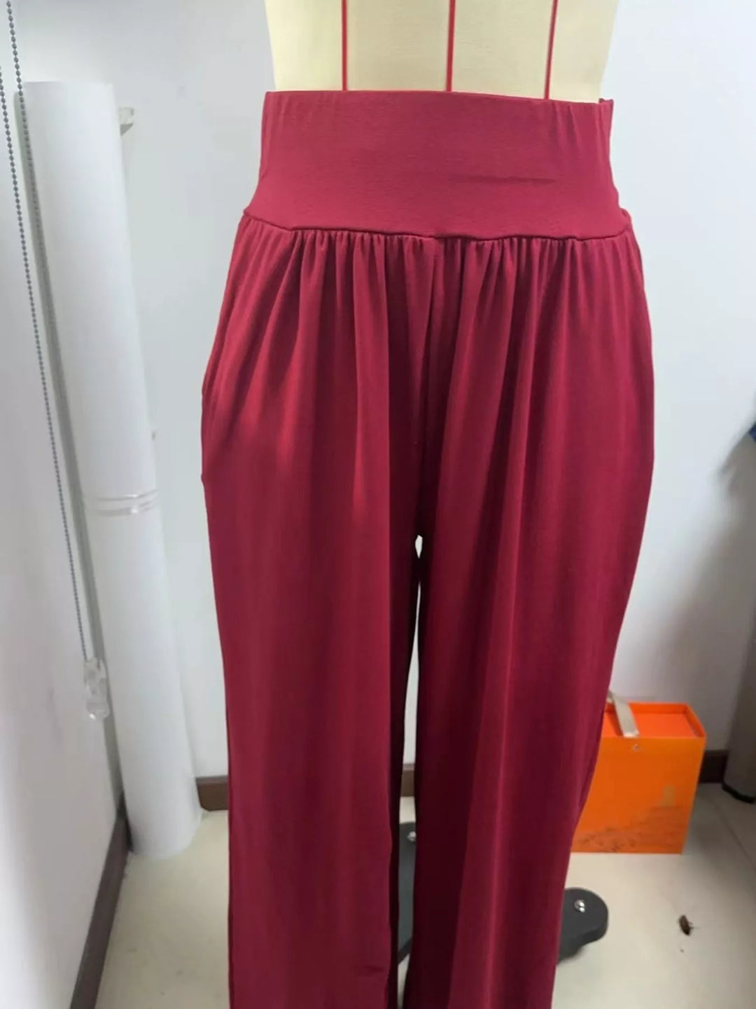 Crimson high waisted wide leg pants, shown indoors with the wide waistband