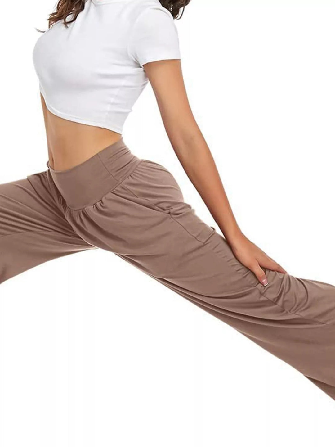 Mocha high waisted wide leg pants, worn with a white crop top in a yoga stretch