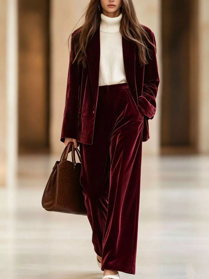 Burgundy velvet-look blazer and wide leg pants set, walking with a brown tote
