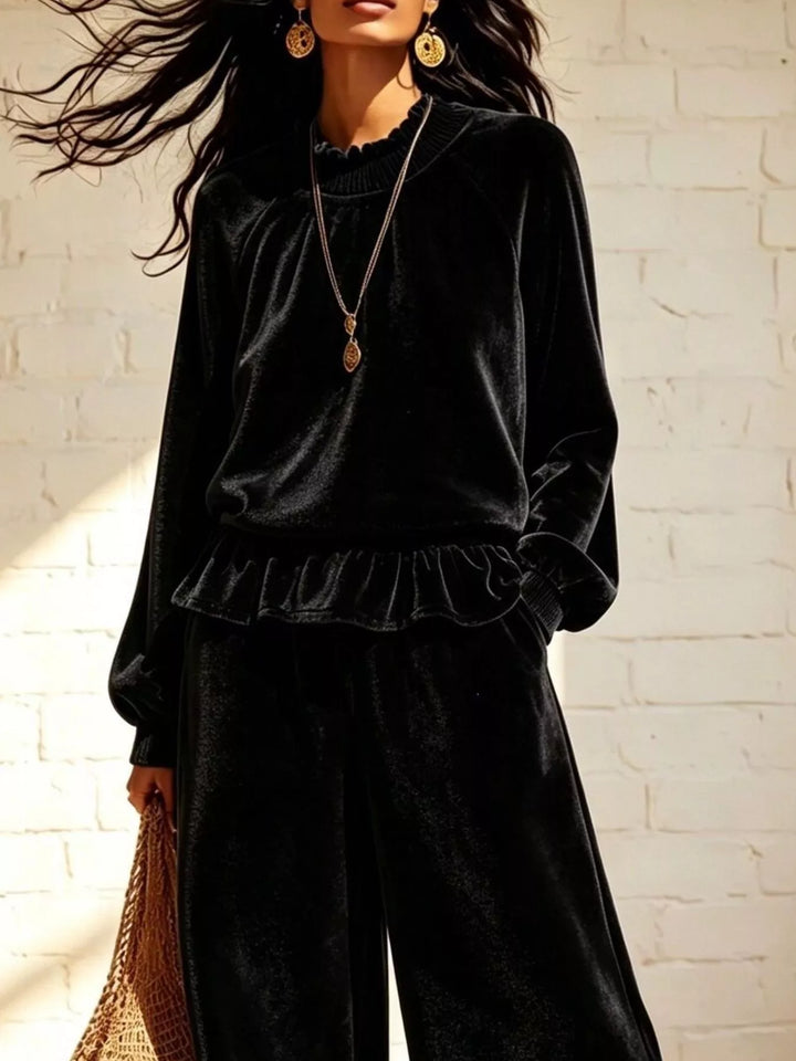 Close-up of the black peplum top with ruffle hem and pendant necklace