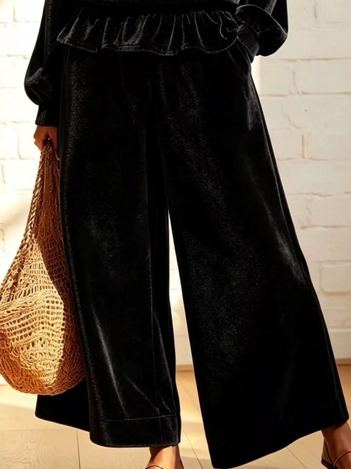 Black wide leg pants with peplum hem above, close-up of the lower half