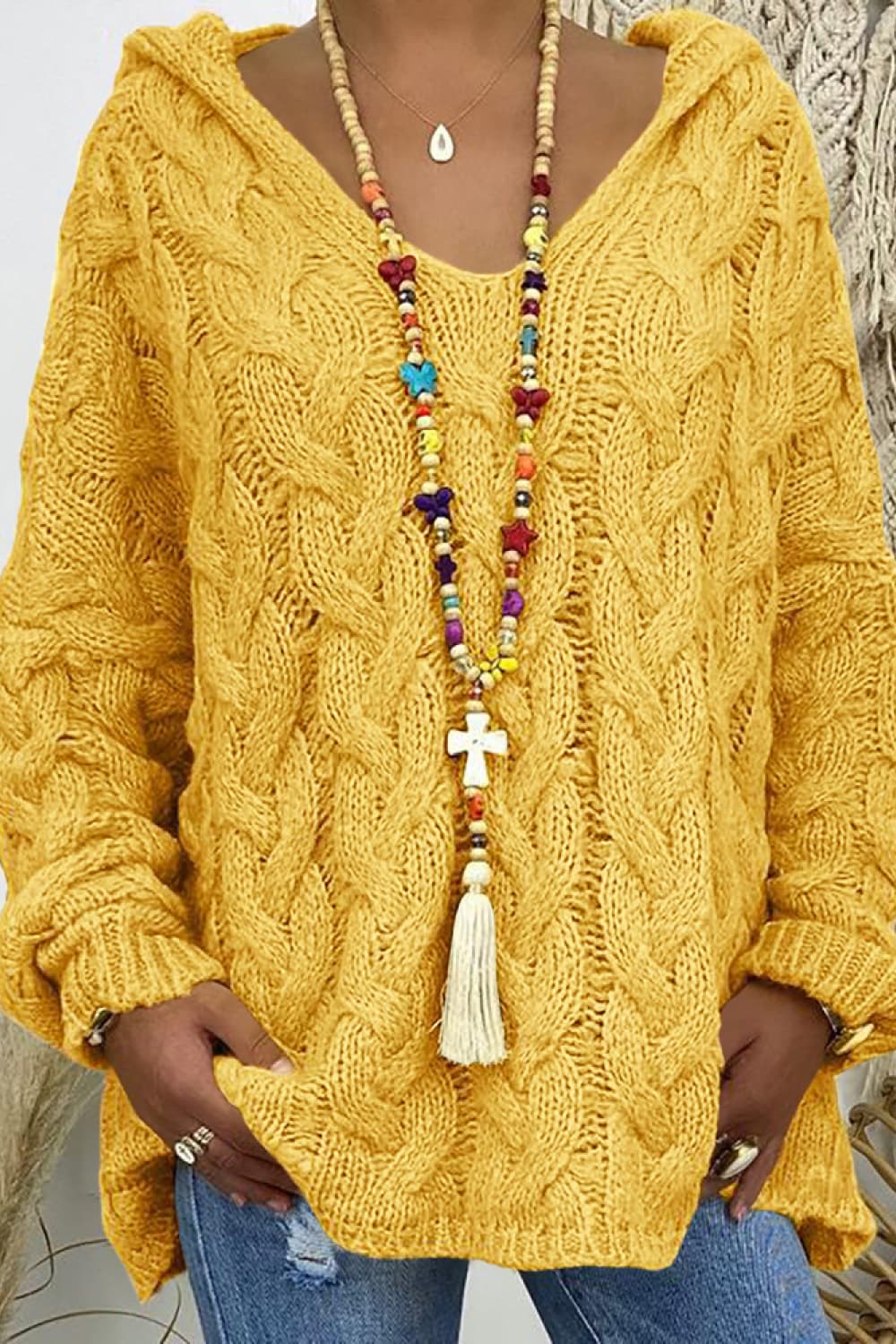 Mustard yellow cable knit hooded sweater, close-up of the V neck and bead necklace