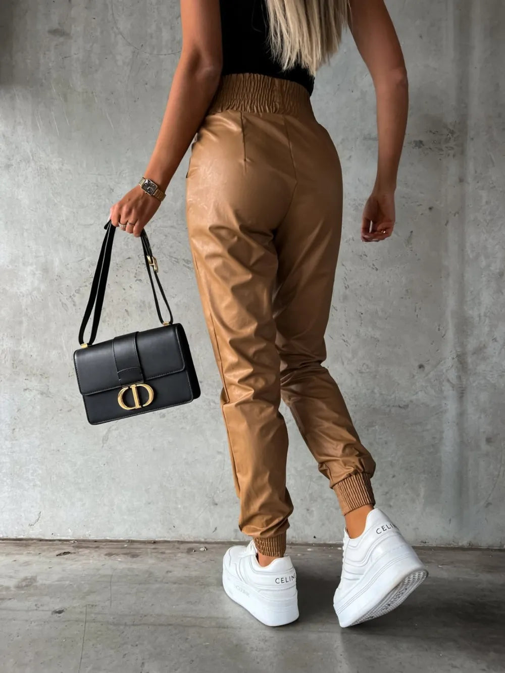Back view of camel jogger pants styled with sneakers and a black bag