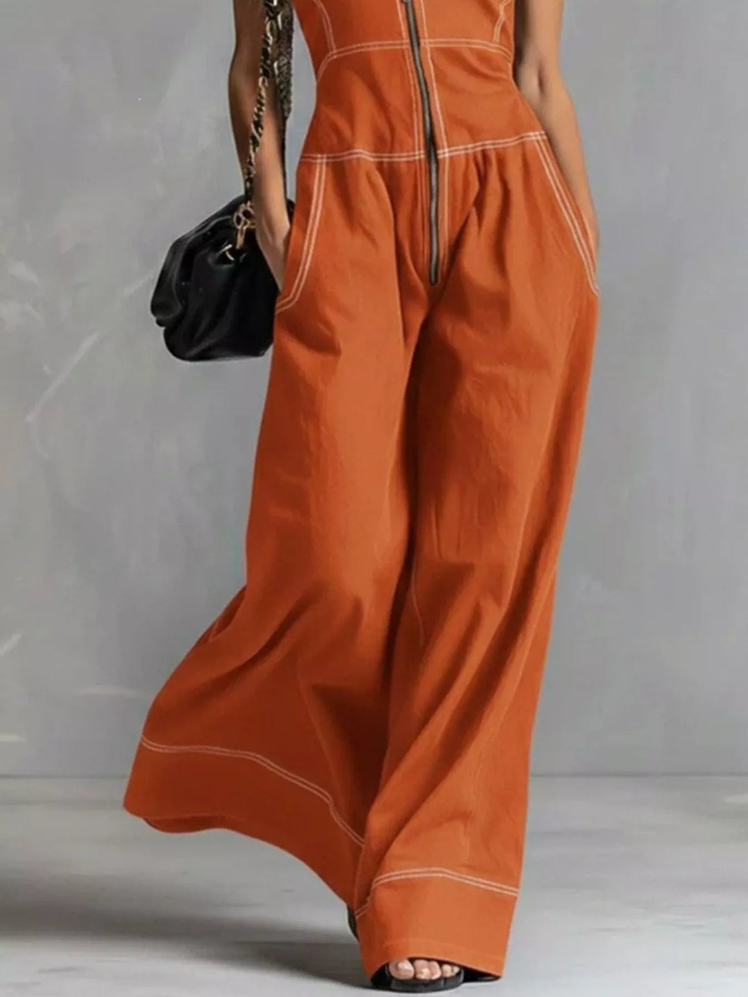 Close-up of the burnt orange zip front jumpsuit with flowing wide legs