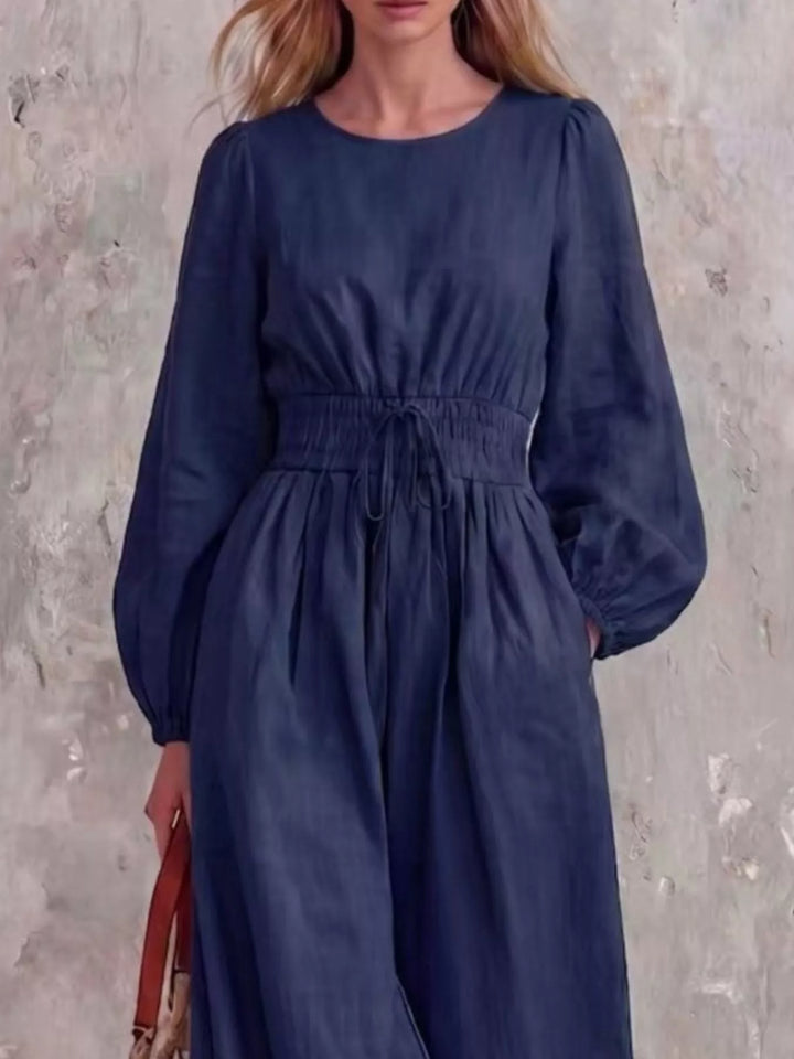 Navy jumpsuit with cinched waist and balloon sleeves, three quarter view