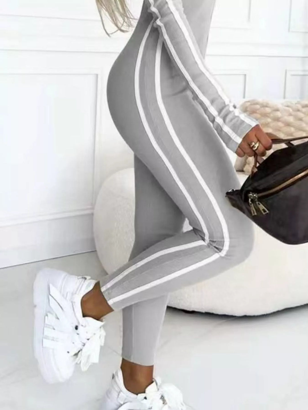Gray striped jumpsuit from the hip down with white sneakers