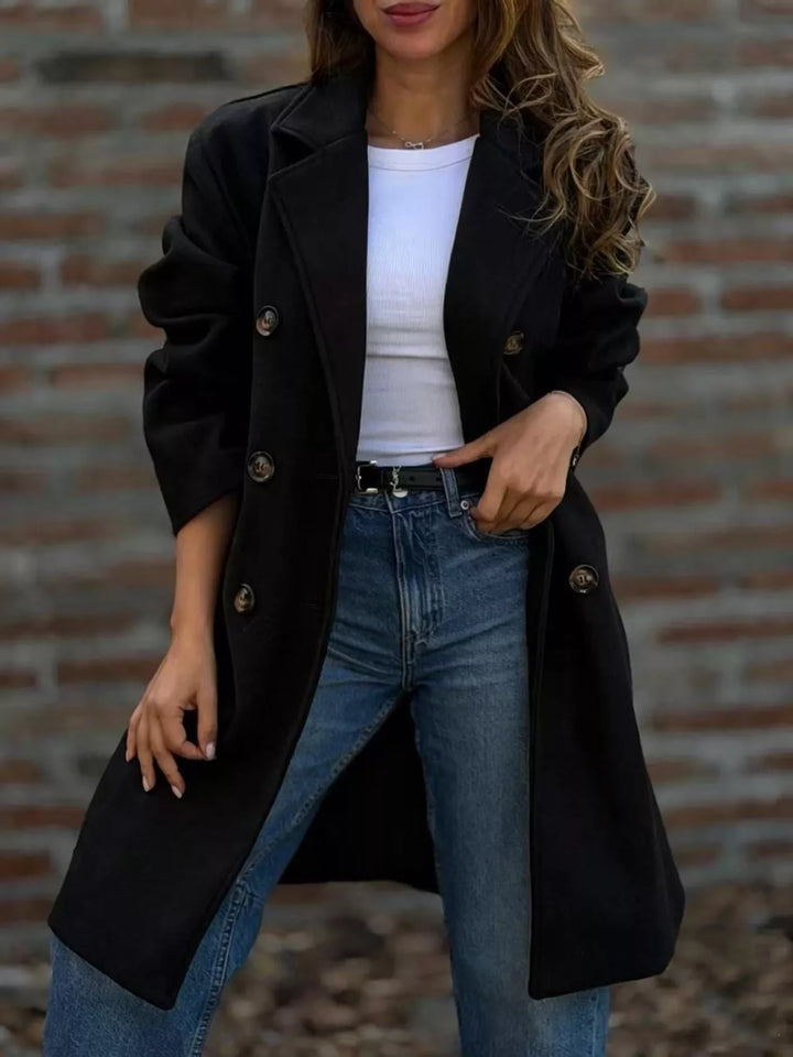 Black longline double breasted coat with notch lapel, worn open over jeans