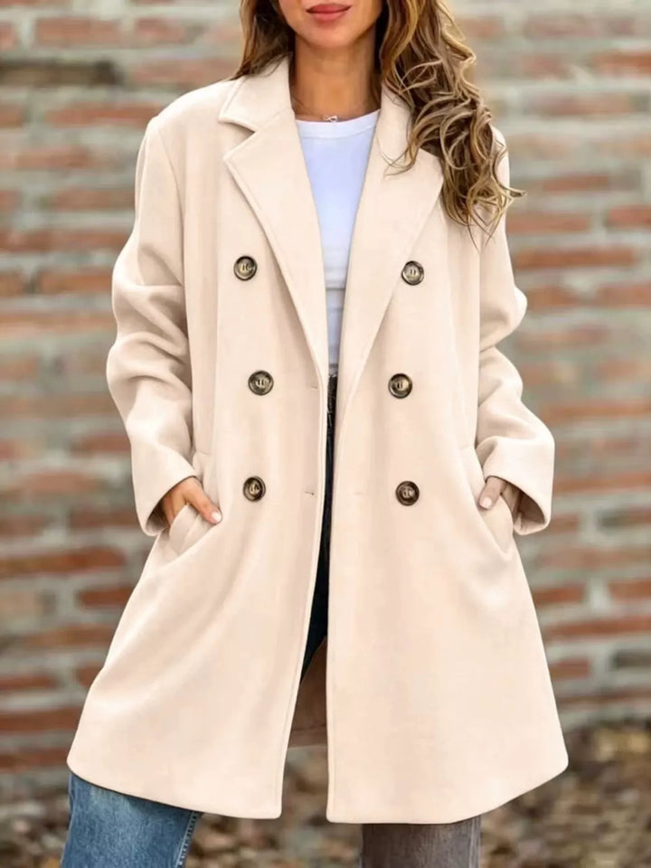 Cream longline double breasted coat buttoned front, hands in pockets with jeans