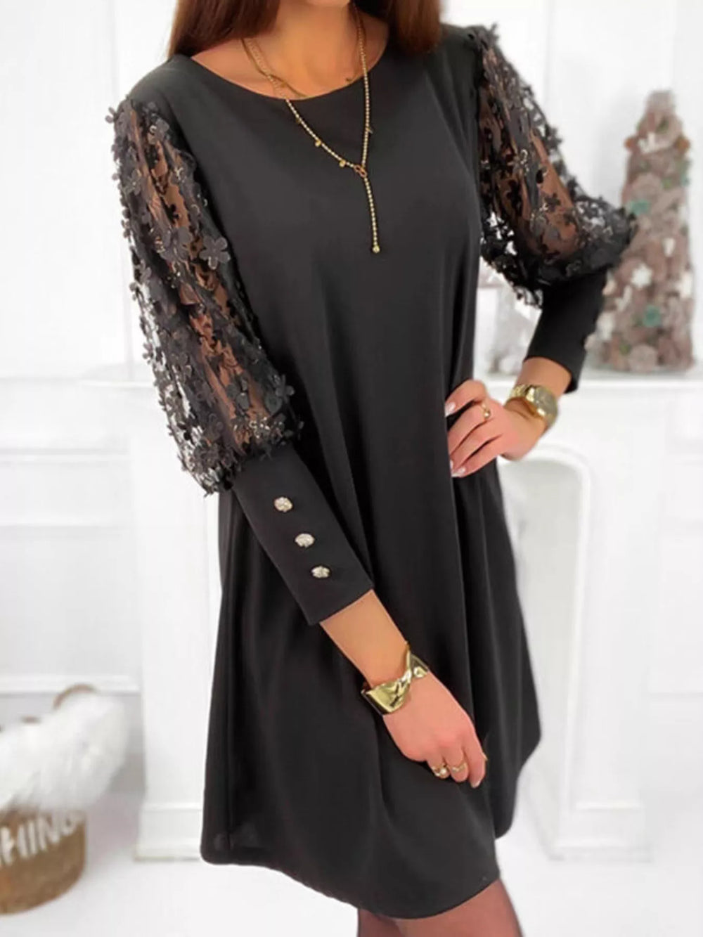 Black mini dress worn on a model, showing the sheer floral lace sleeves