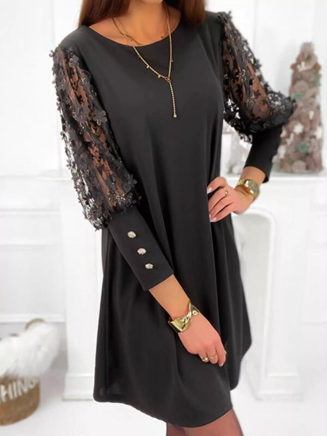 Black mini dress worn on a model, showing the sheer floral lace sleeves