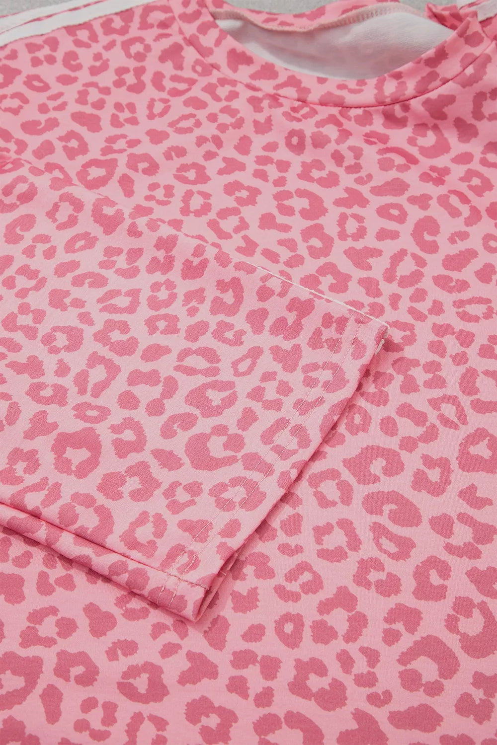 Pink leopard print sleeve and top fabric laid flat, close-up