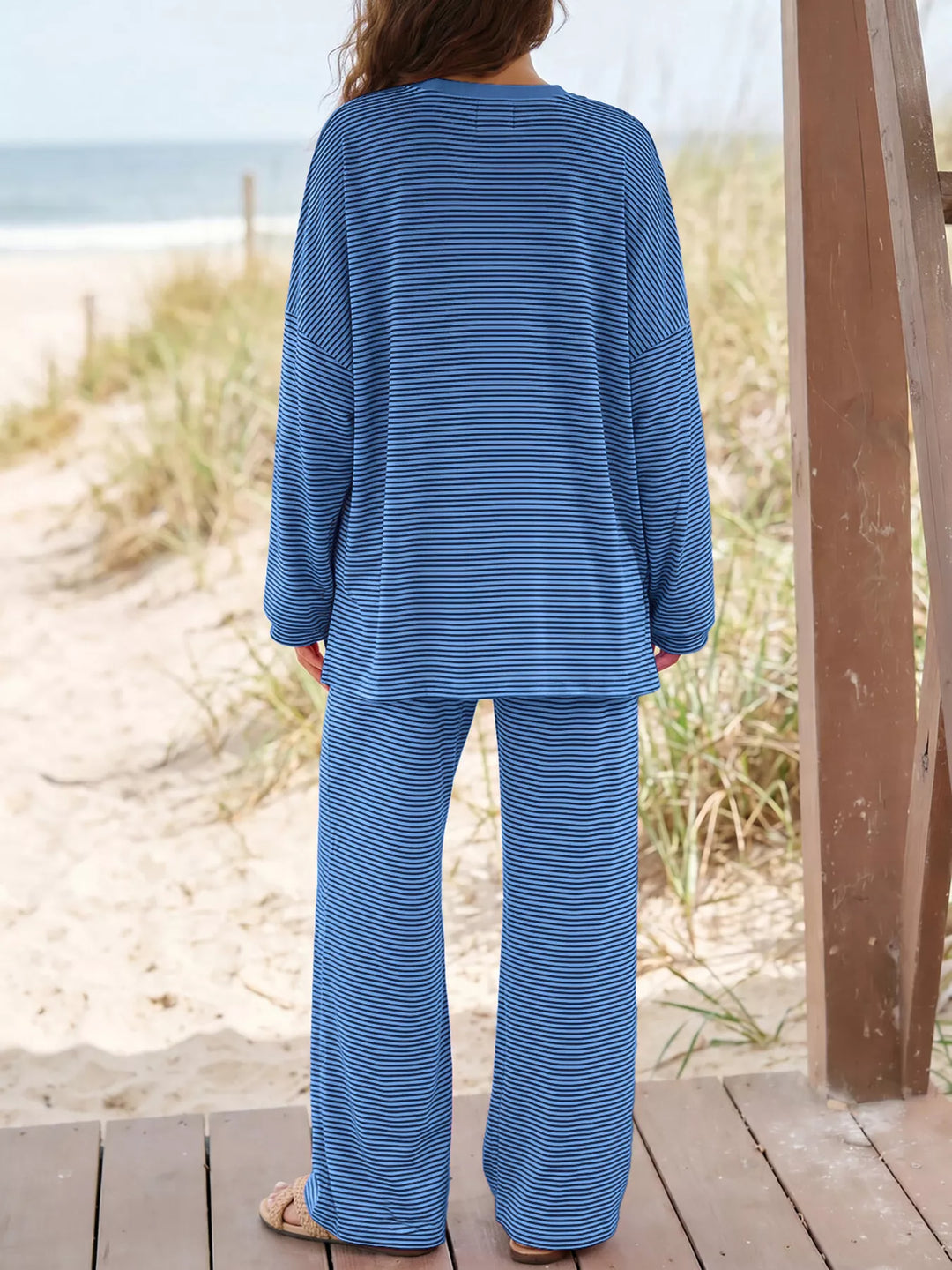 Back view of the blue oversized top and wide leg pants on a beach deck