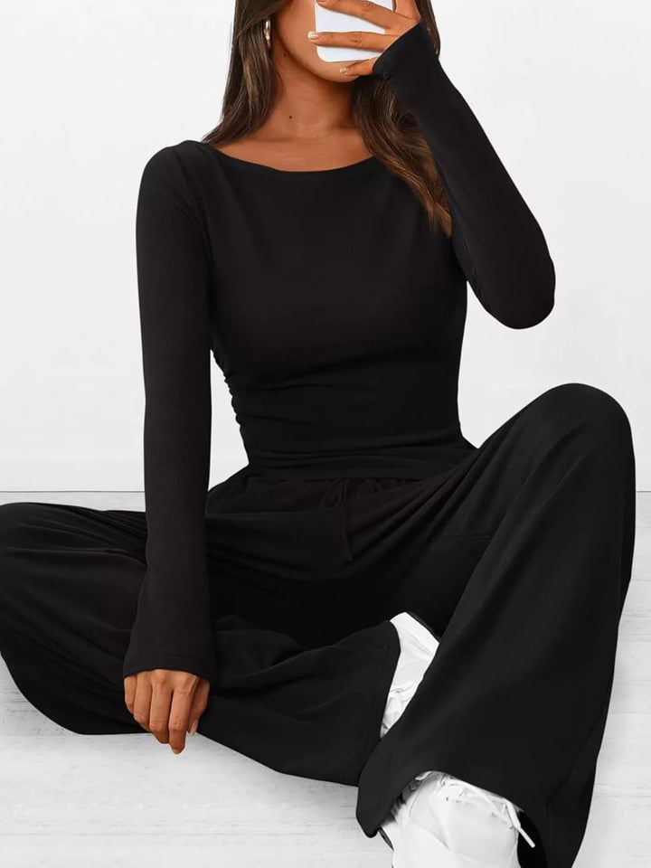 Black ribbed knit ruched top and wide leg pants, seated pose with white sneakers