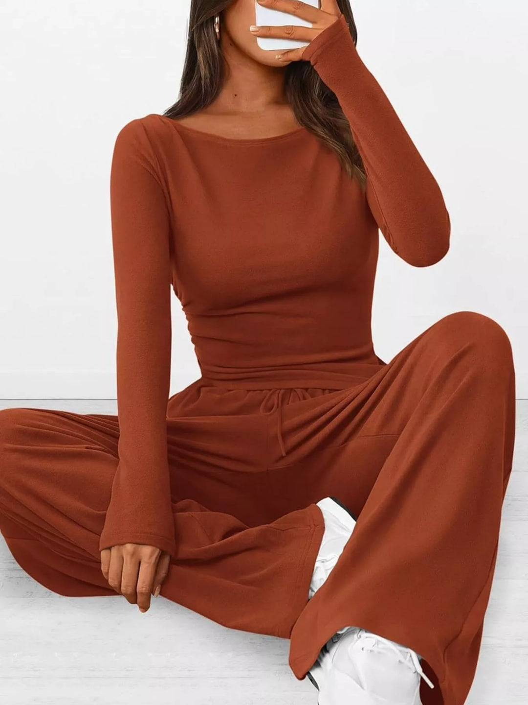 Rust ruched ribbed top and wide leg pants, seated pose close to the camera
