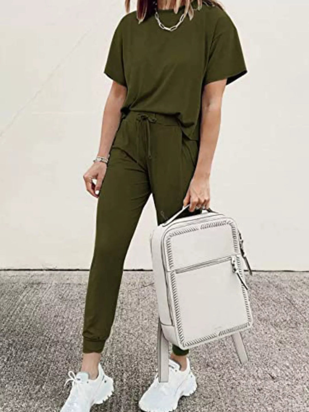 Army green lounge set worn while holding a white backpack at the side