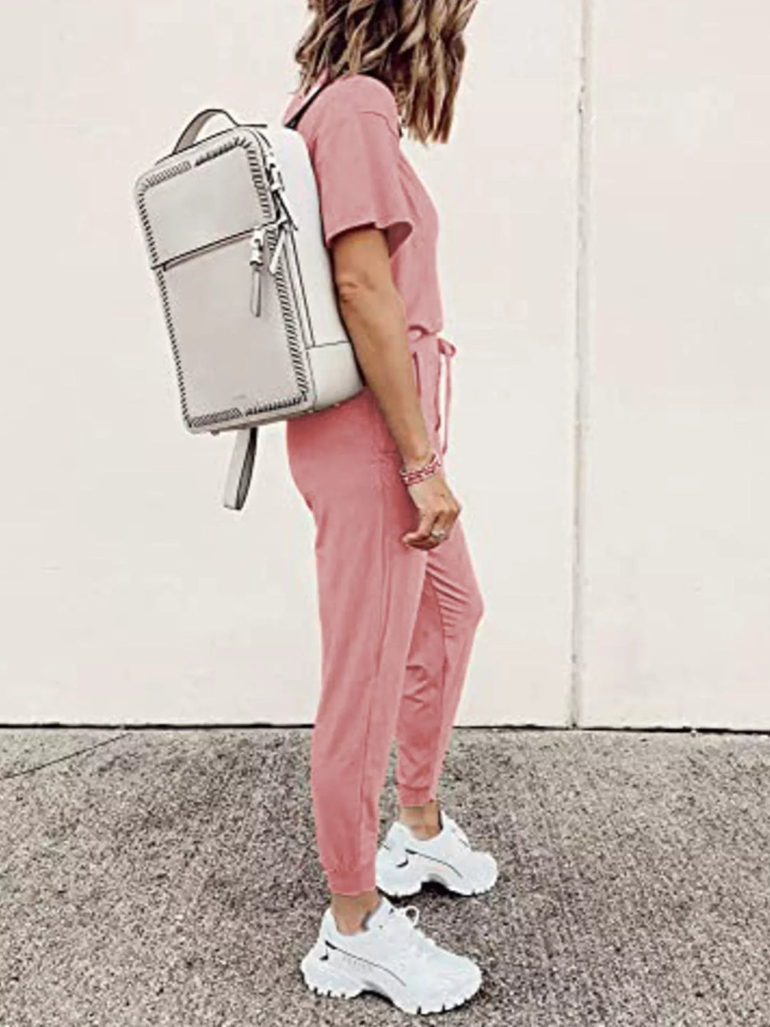 Dusty pink tee and jogger set seen from the side with a white backpack